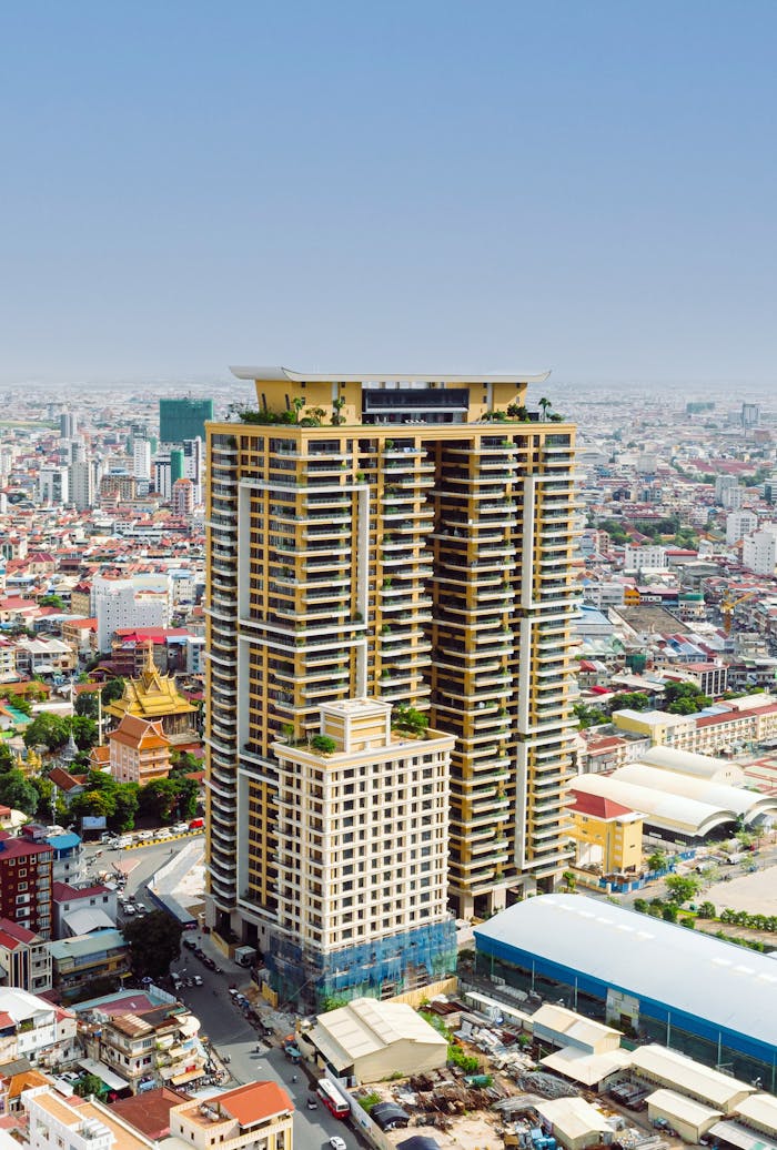 Aerial view of a modern skyscraper amidst an urban city landscape with diverse architecture.